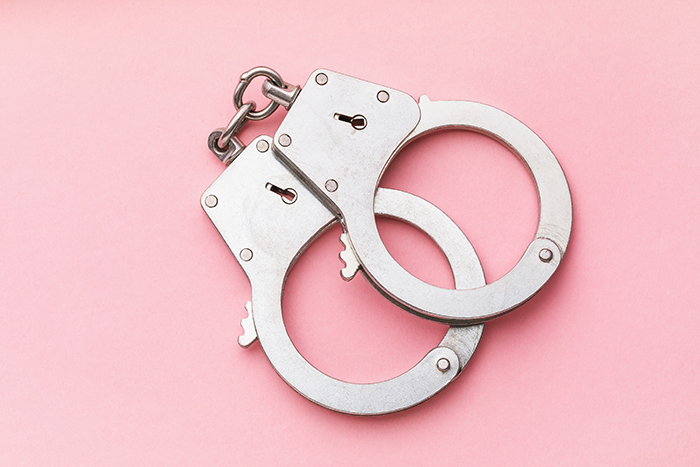 Handcuffs laying on a pink background