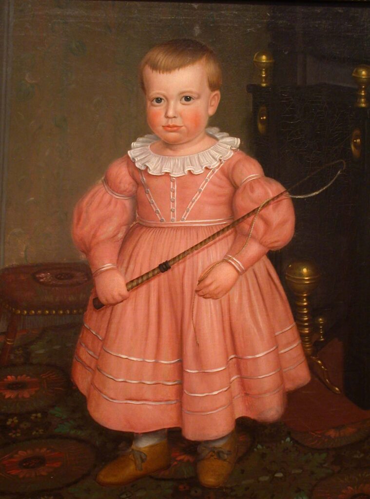 Young boy with a whip wearing a pink dress