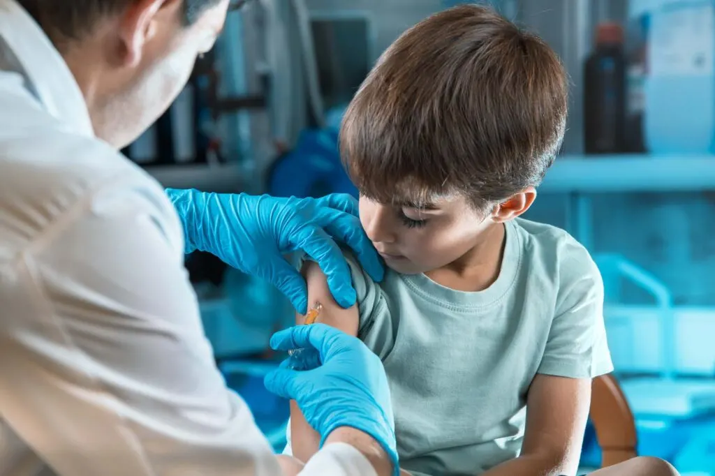 Doctor holding syringe for child in a blue room