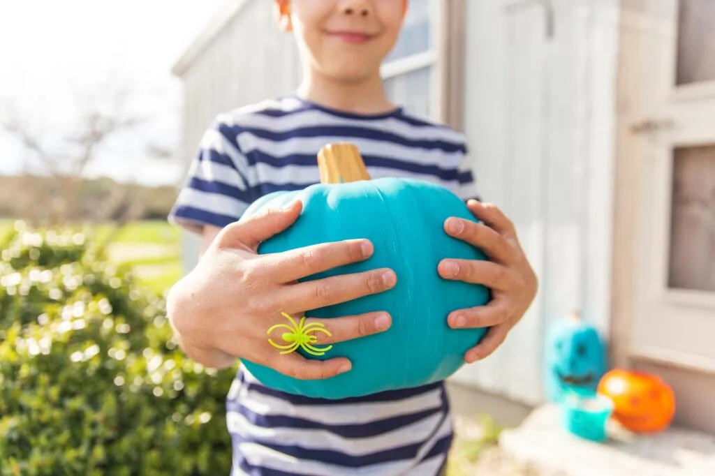 Boy holding Halloween teal pumpkin