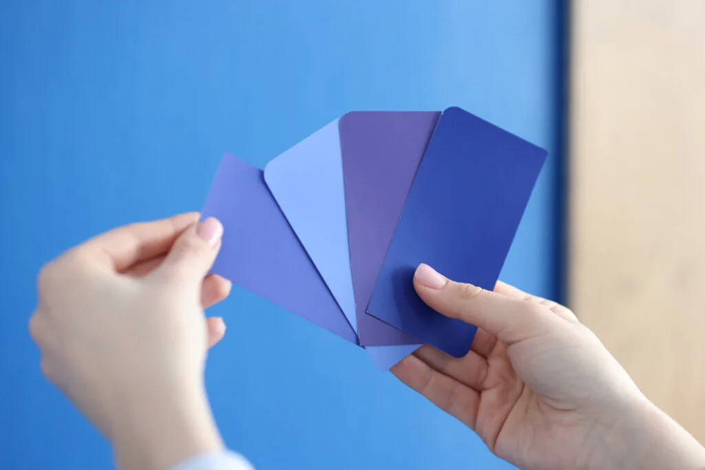 Hands holding different shade, tint, and tone of blue papers