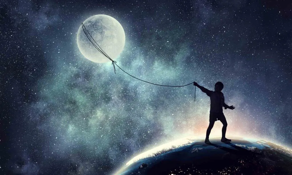Child playing kite with the moon in a colorful dream and blue sky