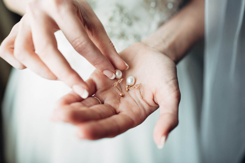 Bride holding white pearl earrings
