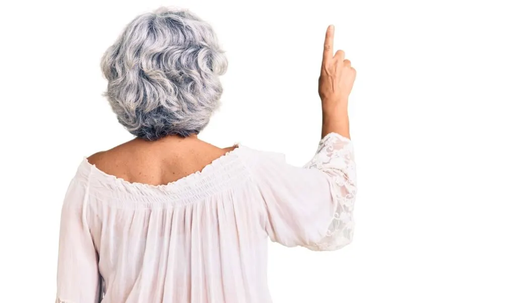 Senior woman with gray hair pointing finger upwards