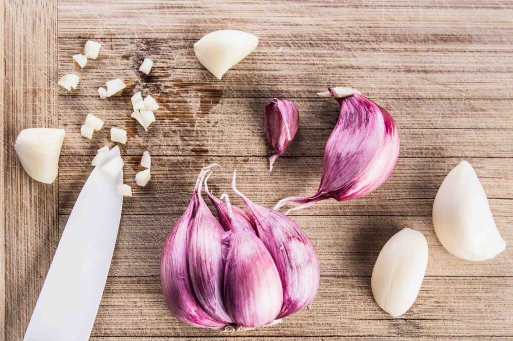 Purple Garlic bulbs on wooden chopping board