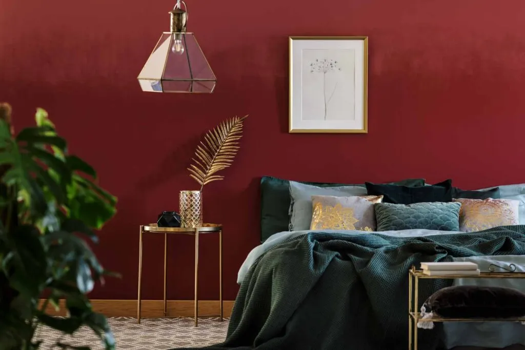 Red bedroom with green blanket with golden furniture