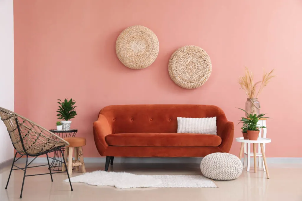 Pink wall and orange couch in a living room